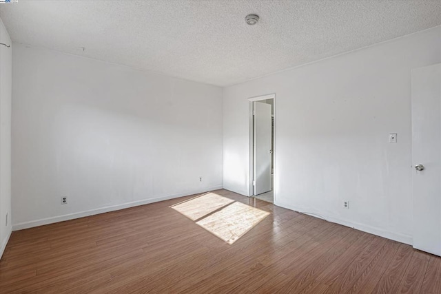 empty room featuring hardwood / wood-style flooring and a textured ceiling