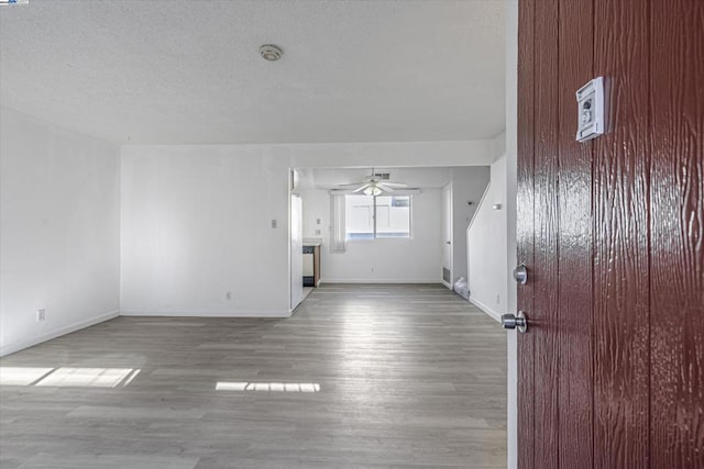 unfurnished living room with a textured ceiling, light hardwood / wood-style floors, and ceiling fan