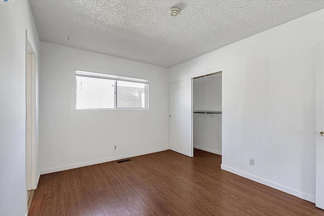 unfurnished bedroom with dark hardwood / wood-style flooring, a closet, and a textured ceiling