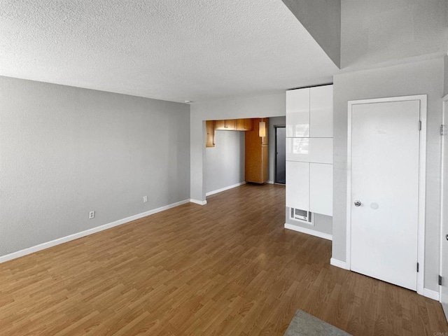 unfurnished living room featuring dark wood-type flooring and a textured ceiling