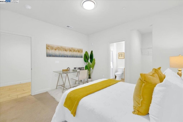 bedroom with light colored carpet and connected bathroom