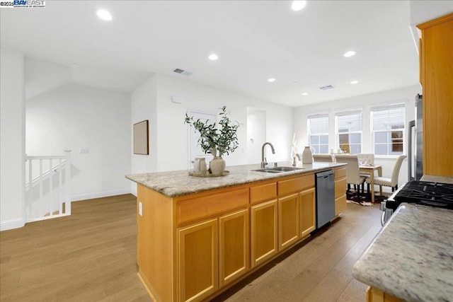 kitchen with sink, light hardwood / wood-style flooring, appliances with stainless steel finishes, light stone countertops, and a kitchen island with sink