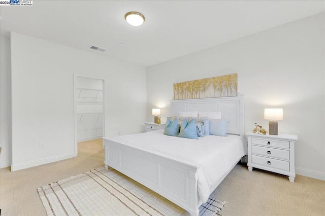 bedroom featuring light colored carpet and a spacious closet