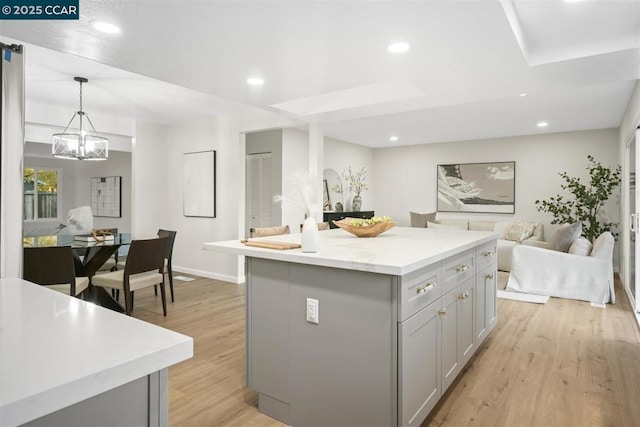 kitchen with a kitchen island, light hardwood / wood-style flooring, gray cabinetry, and decorative light fixtures