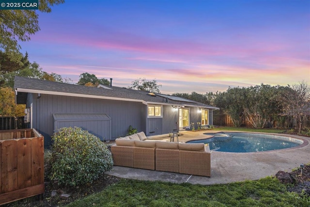 pool at dusk with a patio area and outdoor lounge area