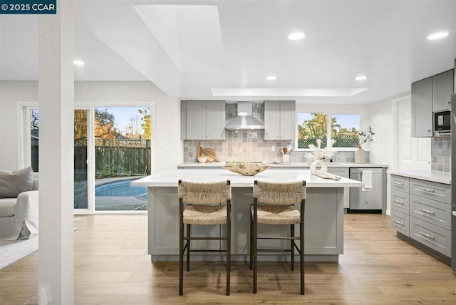 kitchen featuring gray cabinetry, wall chimney exhaust hood, and a kitchen island