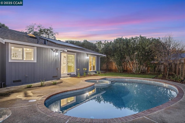 pool at dusk featuring an in ground hot tub and a patio area