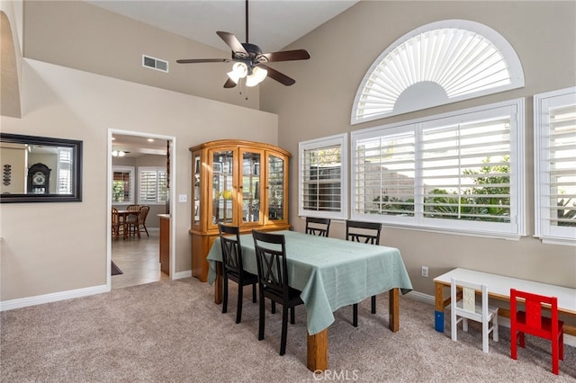 carpeted dining area featuring ceiling fan and a high ceiling