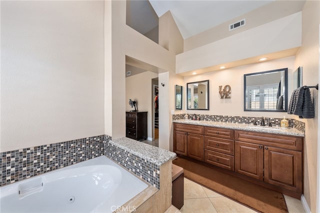 bathroom featuring a relaxing tiled tub, vanity, and tile patterned flooring