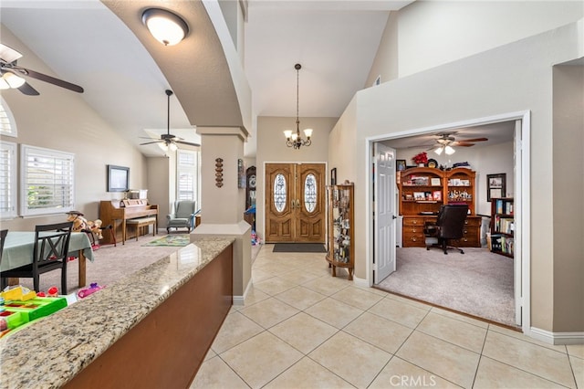 entrance foyer with high vaulted ceiling, ceiling fan with notable chandelier, and light tile patterned floors