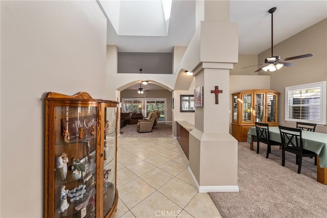 foyer entrance featuring ceiling fan, a towering ceiling, and light tile patterned floors