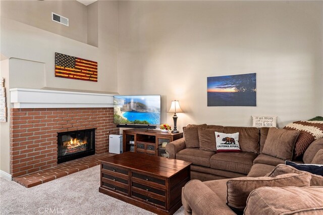 living room with a towering ceiling, a fireplace, and carpet