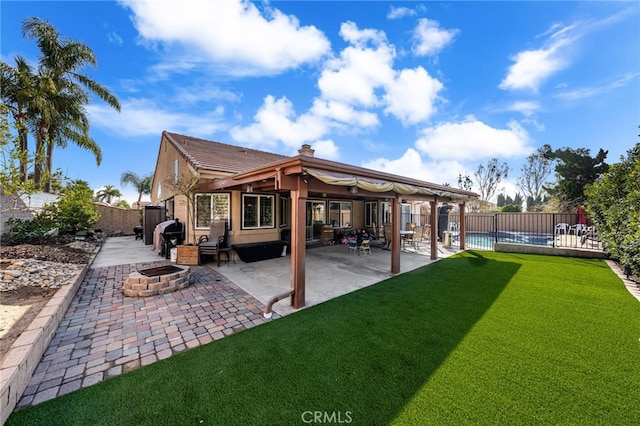 back of property with a patio, a swimming pool, a yard, and an outdoor fire pit