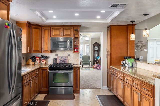 kitchen with light stone counters, stainless steel appliances, a raised ceiling, and hanging light fixtures