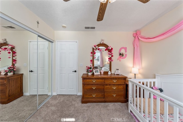 carpeted bedroom with ceiling fan, a textured ceiling, and a closet