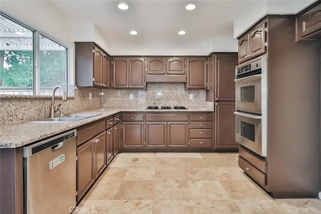 kitchen featuring stainless steel appliances, tasteful backsplash, sink, and dark brown cabinetry