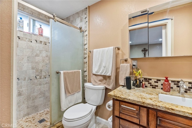 bathroom featuring vanity, toilet, a shower with door, and backsplash