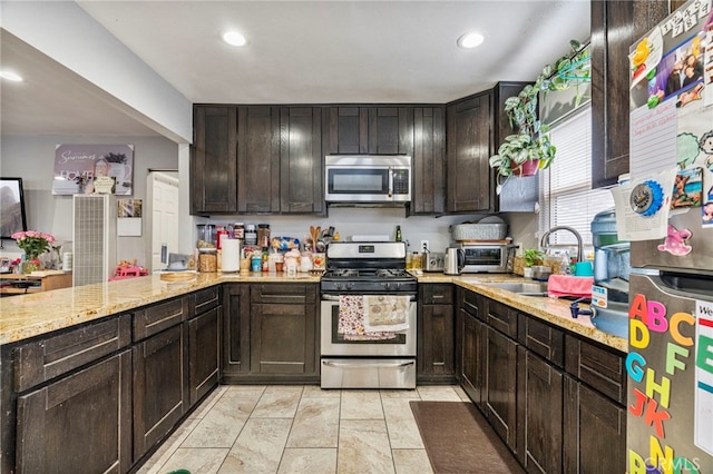 kitchen featuring light stone countertops, appliances with stainless steel finishes, sink, and dark brown cabinets