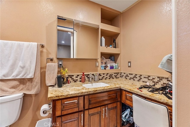 bathroom featuring vanity, decorative backsplash, and toilet