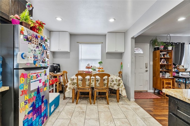 kitchen with white cabinetry, light stone countertops, stainless steel fridge, and light hardwood / wood-style floors