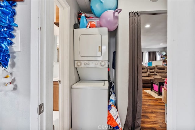 laundry area with stacked washer / dryer and wood-type flooring