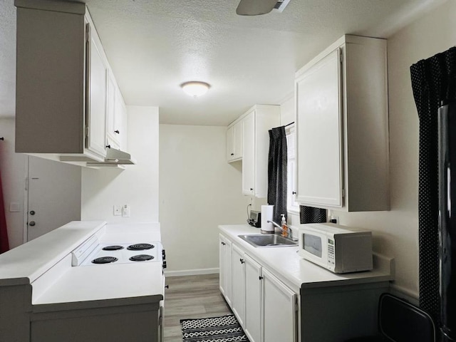 kitchen featuring white cabinetry, sink, hardwood / wood-style floors, and a textured ceiling