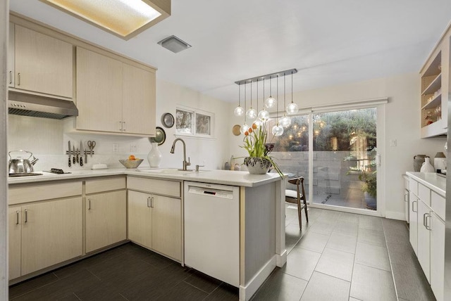 kitchen featuring sink, white dishwasher, extractor fan, decorative light fixtures, and kitchen peninsula