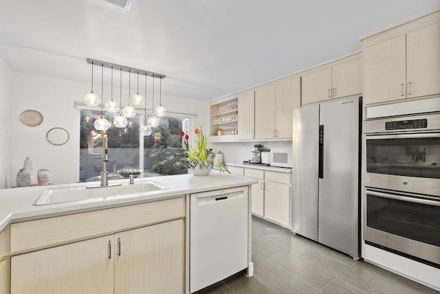 kitchen with pendant lighting, appliances with stainless steel finishes, sink, and cream cabinetry