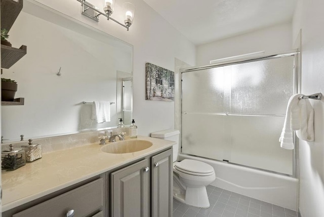 full bathroom with tile patterned flooring, vanity, combined bath / shower with glass door, and toilet