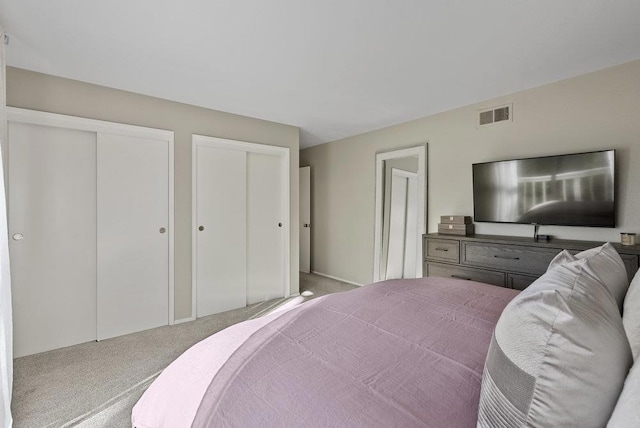 bedroom featuring two closets and light carpet