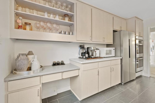 kitchen featuring appliances with stainless steel finishes, dark tile patterned flooring, and cream cabinetry