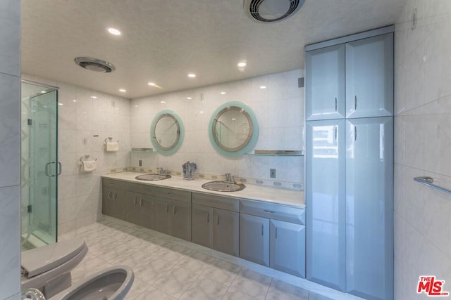 bathroom with a shower with door, a bidet, sink, and tile walls