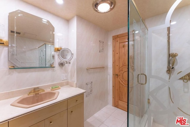 bathroom with vanity, tile walls, tile patterned floors, and walk in shower