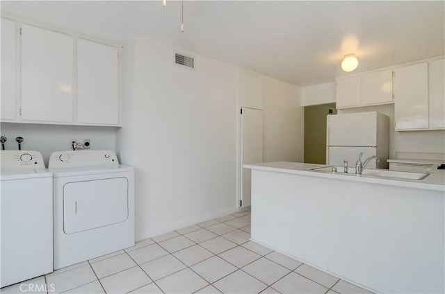 washroom with light tile patterned flooring, washer and clothes dryer, and sink