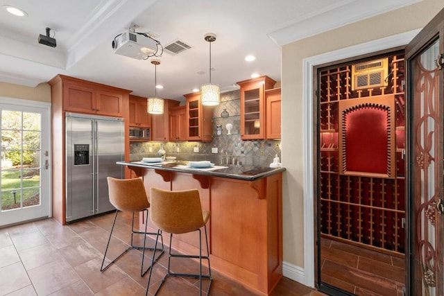 kitchen featuring a breakfast bar, pendant lighting, tasteful backsplash, built in appliances, and crown molding