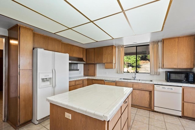 kitchen featuring a center island, sink, white appliances, and light tile patterned floors