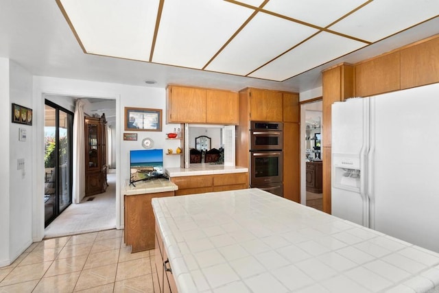 kitchen with light tile patterned floors, tile counters, white fridge with ice dispenser, and stainless steel double oven