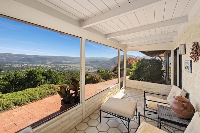 sunroom with a mountain view and beam ceiling