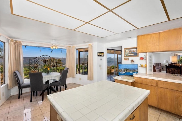 kitchen with a healthy amount of sunlight, tile counters, a kitchen island, and light tile patterned floors