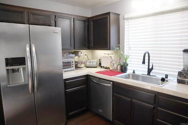 kitchen featuring dark brown cabinetry, stainless steel appliances, dark hardwood / wood-style flooring, and sink