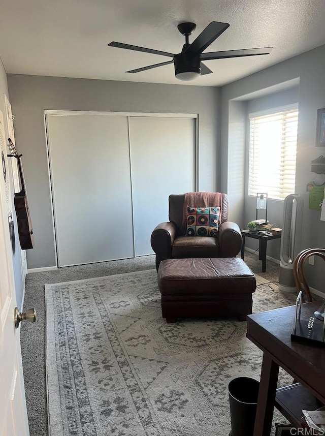 living area with light carpet, a textured ceiling, and ceiling fan