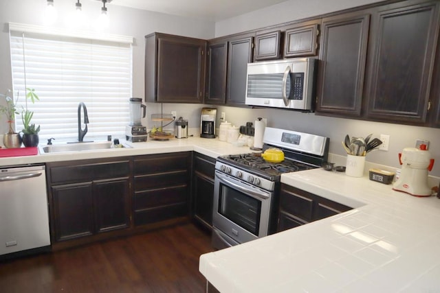 kitchen featuring sink, dark brown cabinets, dark wood-type flooring, and appliances with stainless steel finishes