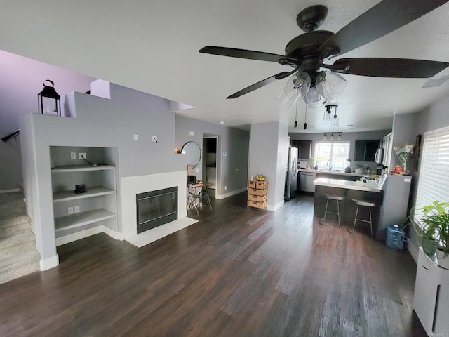 unfurnished living room featuring ceiling fan, built in features, and dark hardwood / wood-style flooring