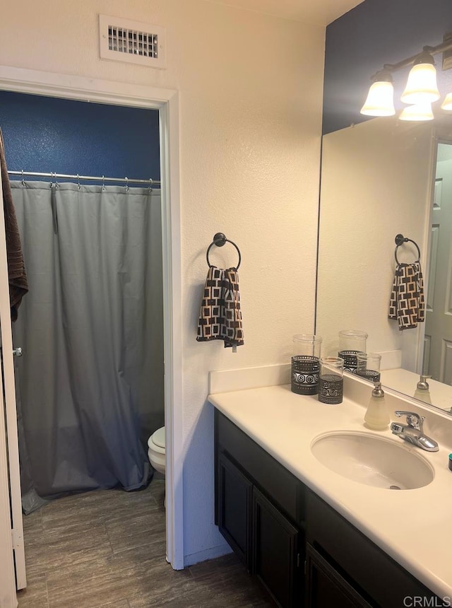 bathroom with wood-type flooring, a shower with shower curtain, vanity, and toilet