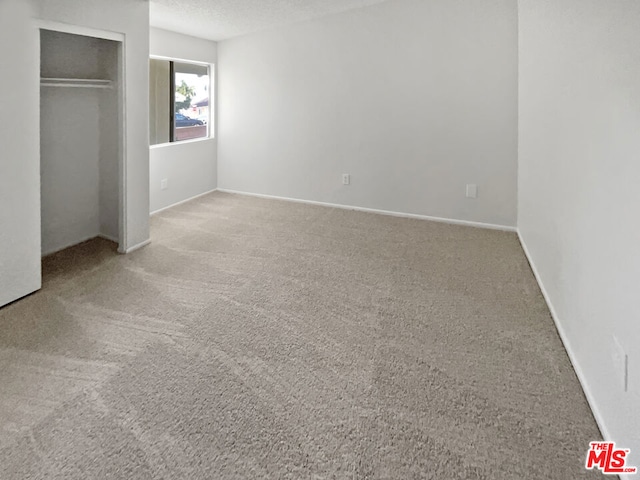 unfurnished bedroom featuring a closet, a textured ceiling, and carpet