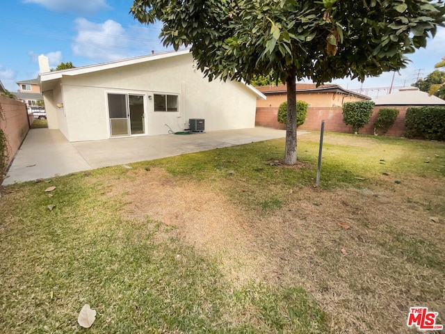 rear view of property with a yard, central AC unit, and a patio