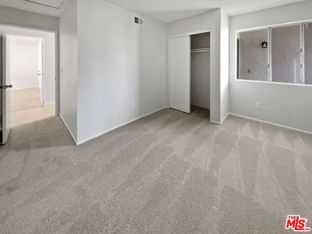 unfurnished bedroom featuring light colored carpet and a closet