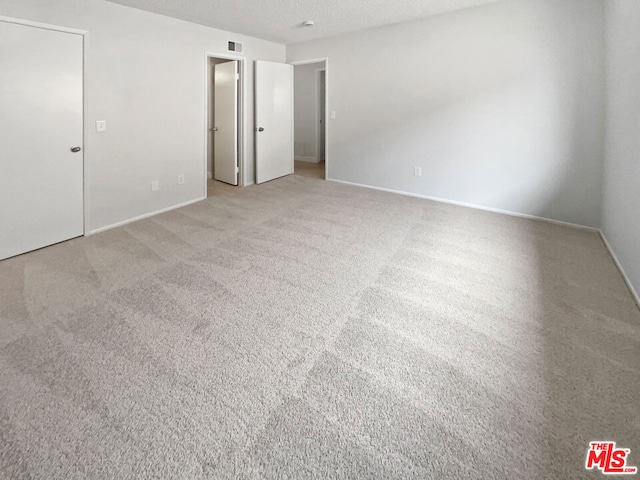 interior space featuring light colored carpet and a textured ceiling