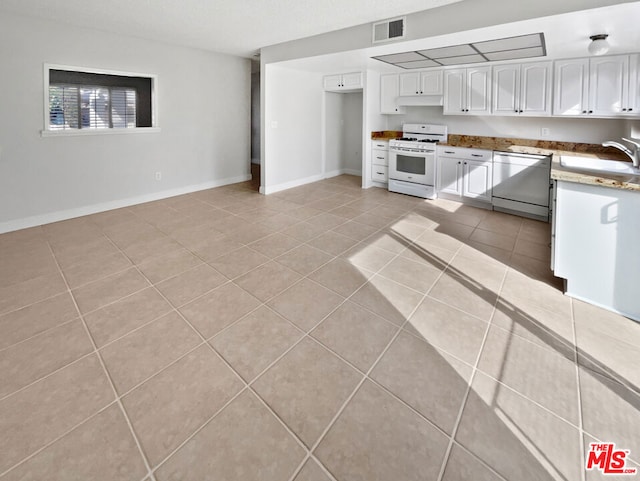 kitchen with light tile patterned flooring, sink, stainless steel dishwasher, white gas range oven, and white cabinets