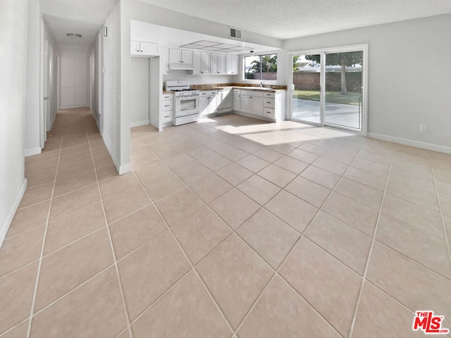 unfurnished living room featuring light tile patterned flooring, sink, and a textured ceiling